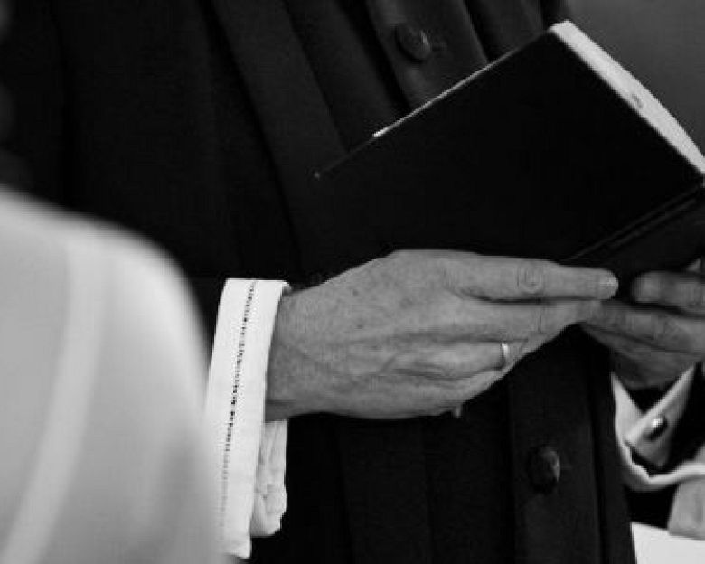 en præst med en bibel og ryggen af en konfirmand