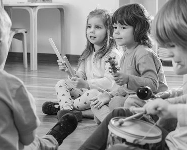 En baby ligger på maven på et rundt tæppe med prikker og kigger ud i luften.