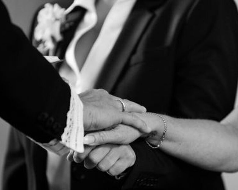 Close-up af hænder fra en præst og et par, der er ved at blive viet.