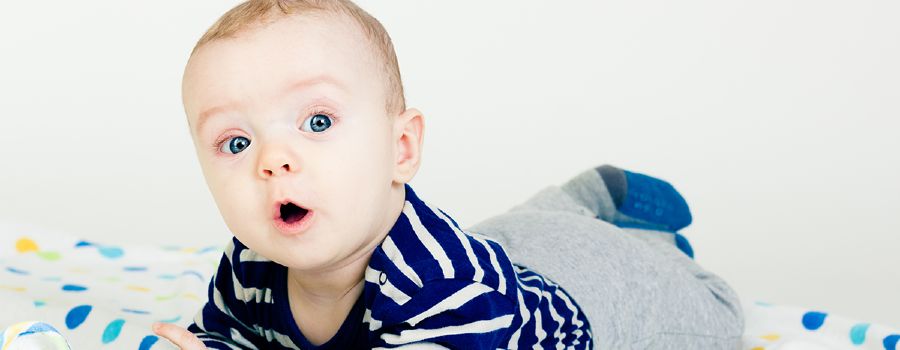 En baby ligger på maven og har munden truttet