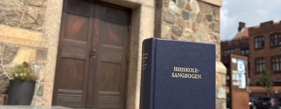 Toppen af en højskolesangbog. I baggrunden ses døren ind til Holstebro Kirke